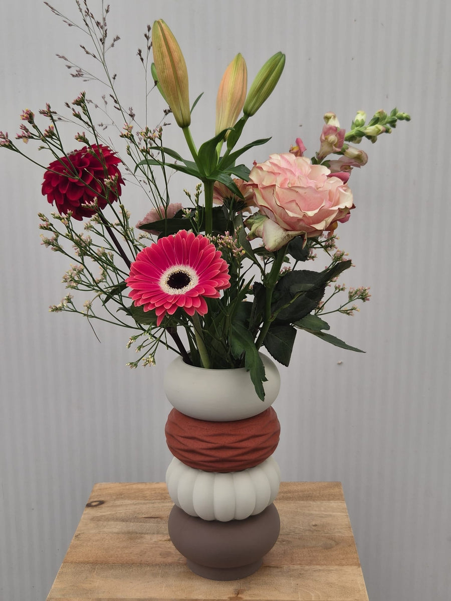 Moduvase van vier secties met een boeket van lelies, gerbera en roos