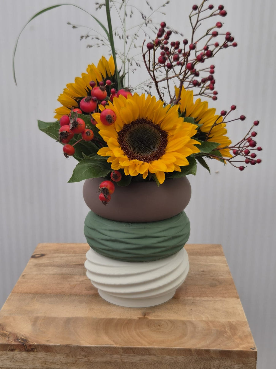 Moduvase van drie secties met zonnebloemen en rozenbottels